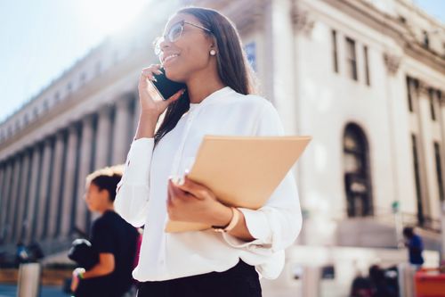 Girl walking with study folder whilst on phone